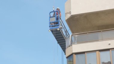 Tarragona, İspanya - 2 Haziran 2023: İnşaatçılar evin yüksekliğinde bir ön cephe asansöründe bir yumrukla çalışıyorlar.