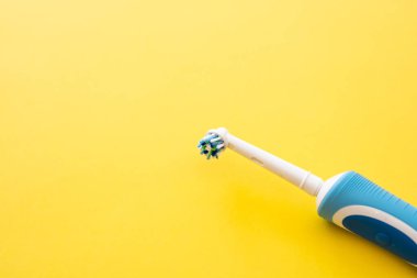 Sarı arka plandaki akıllı elektrikli diş fırçası. Diş fırçalamak için başlık.