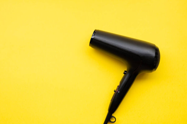 Black hair dryer on blue and yellow paper background