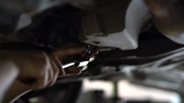 Tamirci, asansörün yakınındaki arabanın fındığını çeviriyor..