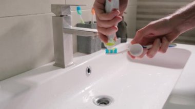 Bir erkek gözü, diş macununu tüpten sıkıp yakın plan fırçaya yapıştırır..