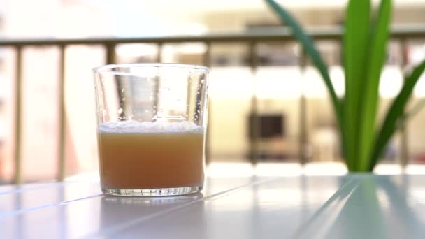 在一个靠近白桌的玻璃杯中溶解一个气体演化的气泡片的过程 — 图库视频影像