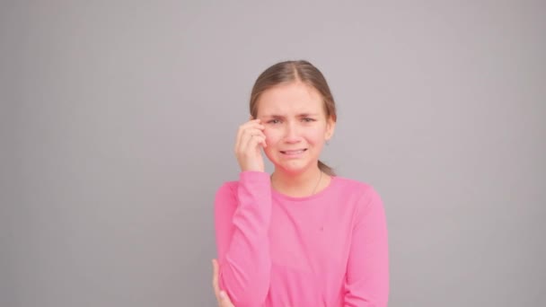 一个穿着粉色T恤的小女孩在哭泣和尖叫 在一个灰色背景的工作室里的视频 一个女孩的特写 — 图库视频影像