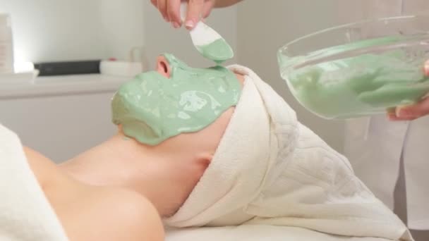 年轻女子的脸被绿色保湿海藻酸钠面具覆盖在美容院 戴上化妆品面具 — 图库视频影像