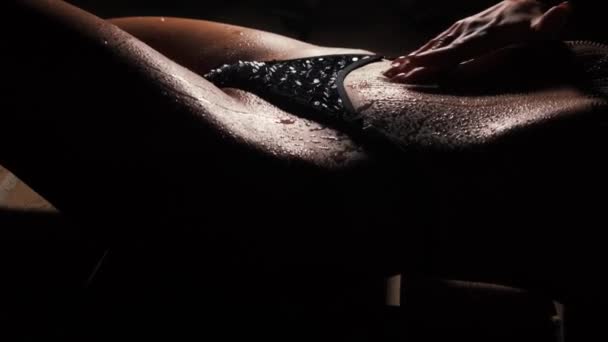一个水滴在身上的女孩 一个漂亮的腹部在黑暗的背景下把她的手放在身体上 — 图库视频影像