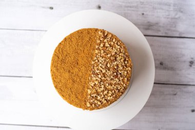 Ev yapımı ballı pasta. Ekşi kremalı. Tahta masada fındıklı..