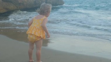 Deniz kıyısında küçük bir kız dalgalara bakıyor..