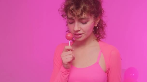 분홍색 배경에 매력적 아름다운 사탕을 있습니다 여자는 사탕을 — 비디오