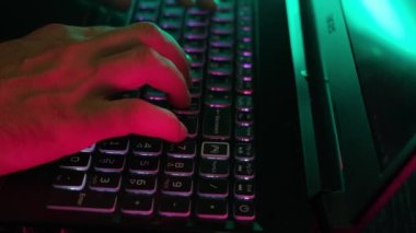 Bir adam dizüstü bilgisayarda el yazısı yazısını neon ışıkla aydınlatır..
