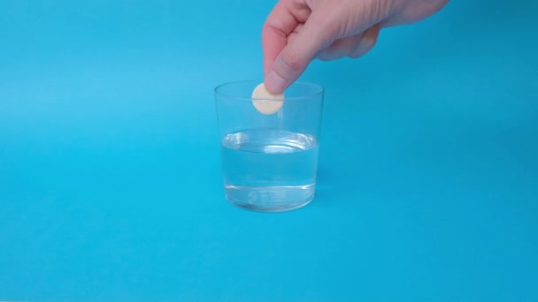 Uma Mão Homem Cai Comprimido Efervescente Copo Água Fundo Azul — Vídeo de Stock