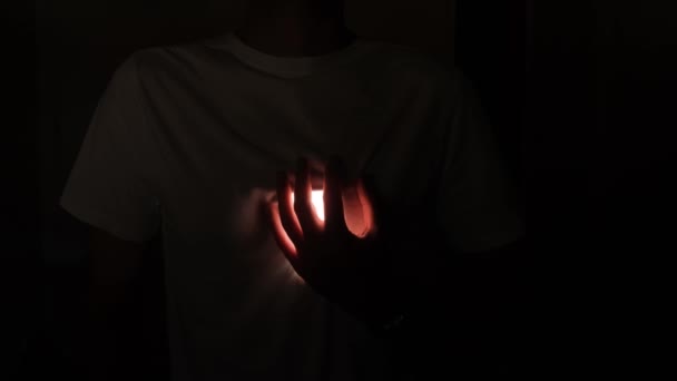 Homem Com Uma Shirt Branca Num Quarto Escuro Segura Mão — Vídeo de Stock