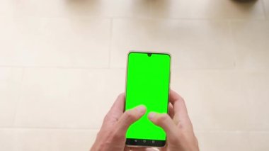 Bir adam elinde yeşil ekranlı, üst görüşlü bir telefon tutuyor. Yavaş çekim.