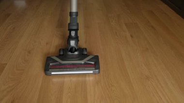 Turbo fırça ve aydınlatma ile kablosuz bir elektrik süpürgesi plastik zemini yakın plan temizler..