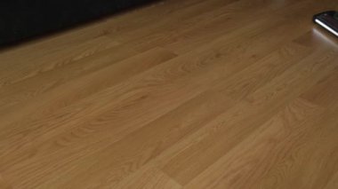 Turbo fırça ve aydınlatma ile kablosuz bir elektrik süpürgesi plastik zemini yakın plan temizler..