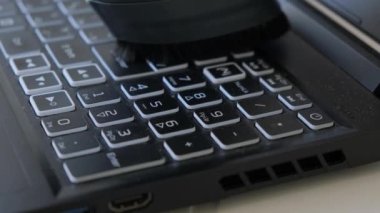 Yakın çekim elektrikli süpürge dizüstü bilgisayardaki klavyeyi temizliyor.