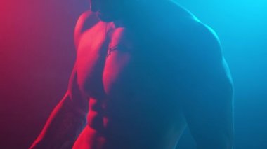 Stüdyodaki genç kaslı adam yeni ışıklar ve dumanla.