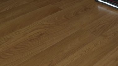 Turbo fırça ve aydınlatma ile kablosuz bir elektrik süpürgesi plastik zemini yakın plan temizler..