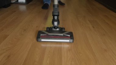 Turbo fırça ve aydınlatma ile kablosuz bir elektrik süpürgesi plastik zemini yakın plan temizler..