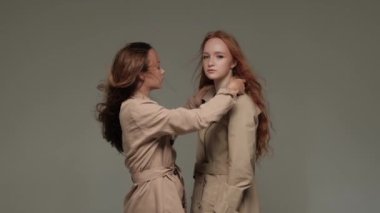 Stüdyoda gri arka planda, trençkotlu iki şık model..