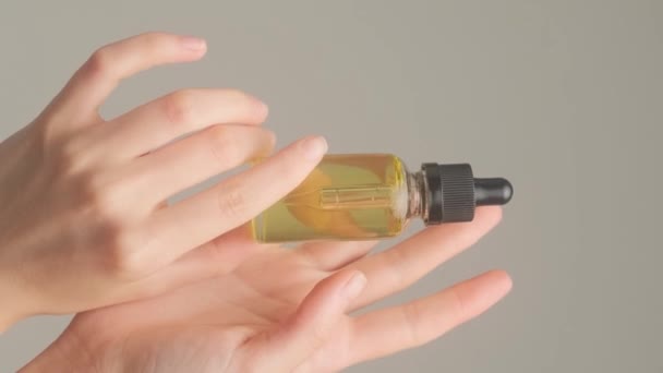 Vackra Kvinnors Händer Håller Kosmetisk Olja Transparent Vit Flaska Grå — Stockvideo