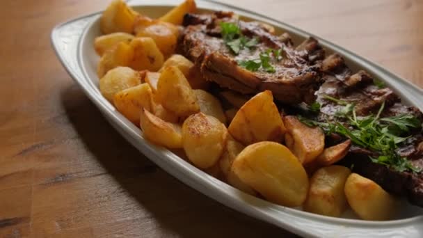 Ein Gericht Mit Kartoffeln Und Schweinerippchen Auf Einem Holztisch Großaufnahme — Stockvideo