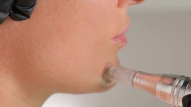 Güzellik uzmanının dermapen 'i ile mikronedling yaparken güzel yaşlı bir kadının yakın plan portresi. Dikey video.