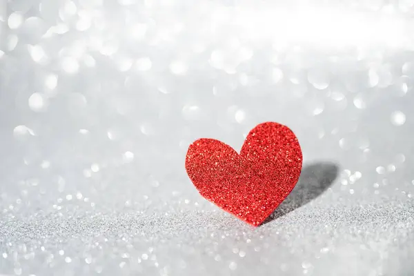 Red heart on a silver background with beautiful bokeh. Valentines Day is the feast of lovers.