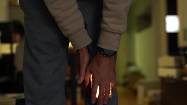 一个穿裤子的男人抱着他疼痛的膝盖 疼痛闪烁着明亮的光芒 — 图库视频影像