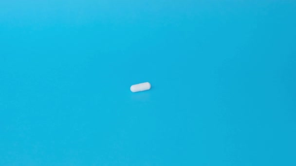 青い背景に白い錠剤を閉じました ハンドはカプセルを取る — ストック動画