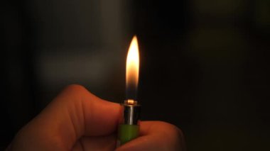 Karanlık arka planda yanan gaz çakmaklarını tutan taşınabilir bir cihaz alev yaratmak için kullanılıyor.