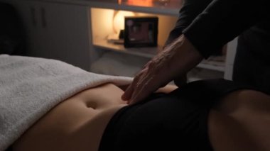 Erkek eller, kadın karnına lenfatik drenaj masajı yapıyor..