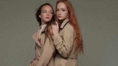 Stüdyoda gri arka planda, trençkotlu iki şık model..