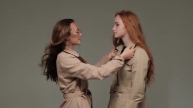 Stüdyoda gri arka planda, trençkotlu iki şık model..