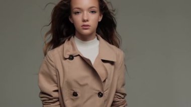 Stüdyoda gri arka planda, trençkotlu iki şık model..