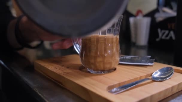バーテンダーは コーヒーの透明なカップにホットミルクをプール — ストック動画