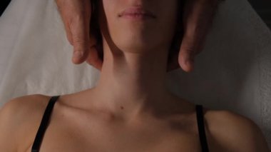 Bir kadının boynuna lenfatik drenaj masajı yapan erkek ellerinin yakın çekimi..