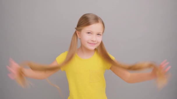 Niña Feliz Con Coletas Llevando Una Camiseta Amarilla Sobre Fondo — Vídeos de Stock