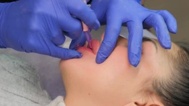 Güzellik salonunda dudaklarında kalıcı makyaj yapan genç bir kadın. Kapat.