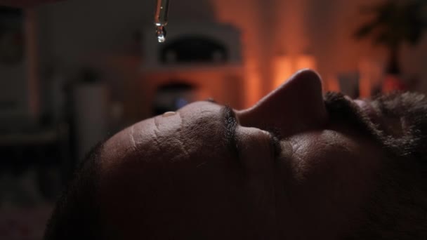 男人的额头上滴着油做按摩 一个英俊男子在温泉中心享受面部按摩的特写镜头 — 图库视频影像