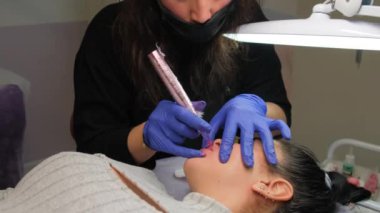 Güzellik salonunda dudaklarında kalıcı makyaj yapan genç bir kadın. Kapat.