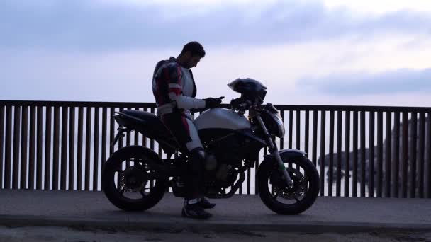 Motociclista Sienta Una Motocicleta Deportiva Mira Teléfono Inteligente — Vídeos de Stock