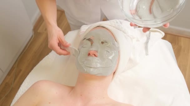 美容室で緑の保湿アルギン酸マスクで覆われた顔を持つ若い女性 化粧品マスクの適用 — ストック動画