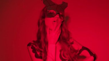 Kırmızı ışıklı bir stüdyoda seksi bir vücut giysisi içinde boynuzları olan şeytan kız..