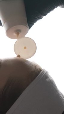 Güzellik uzmanlarının elleri yaşlanma önleyici yüz kremi sürüyor, kadın yüzüne masaj yapıyor. Cilt bakımı. Güzellik tedavisi. Güzel surat. Kadın güzellik portresi. Dikey yakın çekim videosu.