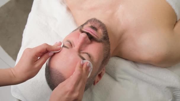 メンズ化粧品 スパセンターのコットンパッドで顔のクレンジング 髭のクローズアップ付き男性の顔 — ストック動画