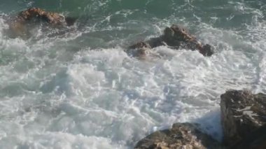 Deniz dalgaları taşların üzerinde yuvarlanıyor