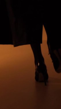 Siyah topuklu ayakkabılı kadın bacakları güzel yürüyüş modeli. Dikey video.