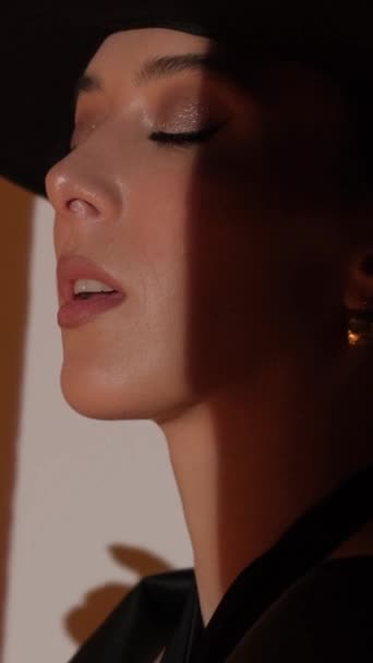 スタジオの女の子のファッション肖像画 黄金の装飾が施された黒い帽子 ジュエリー バーティカルビデオ — ストック動画