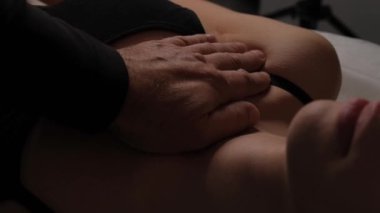 Bir kadının boynuna lenfatik drenaj masajı yapan erkek ellerinin yakın çekimi..