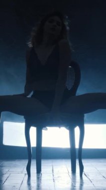 Mavi dumanla erotik dans eden seksi bir kızın silueti. Dikey video.